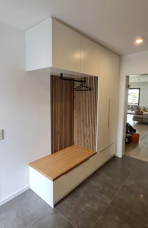 Maßgefertige Garderobe aus einer Kombination von weißen Oberflächen und Holz